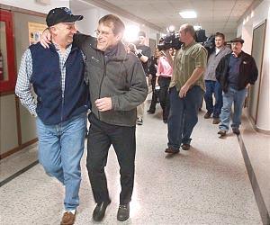 Former Duluth East hockey coach Mike Randolph wraps his arm around Denny Davis (left) as he leaves the Duluth School Board meeting Tuesday night after being reinstated as Duluth East's boys hockey coach for the 2004-05 season. The board voted 5-2 to reinstate Randolph.